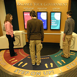 Image of older students performing a balance your government exercise with an interactive display in the Visitor Education Center.